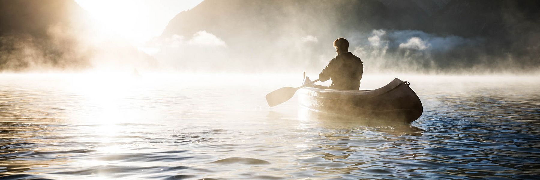 Kanufahrer im Morgennebel auf dem Heiterwanger See in den Bergen